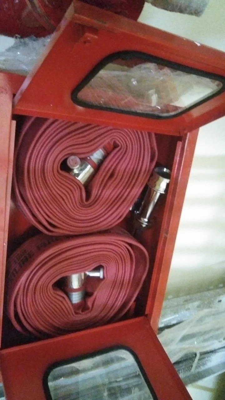 Open fire hose cabinet with coiled hoses and nozzle